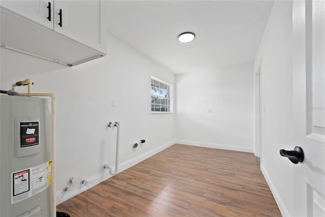 washroom featuring electric water heater, cabinets, hardwood / wood-style floors, and hookup for a gas dryer