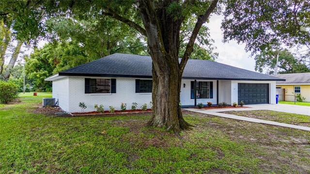 single story home featuring cooling unit, a garage, and a front lawn