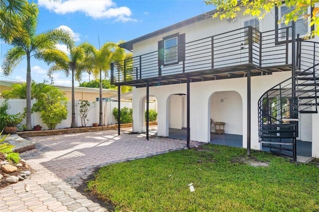 rear view of property with a balcony, a yard, and a patio