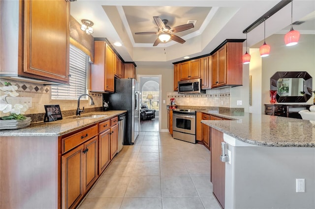 kitchen with stainless steel appliances, sink, a raised ceiling, pendant lighting, and ceiling fan