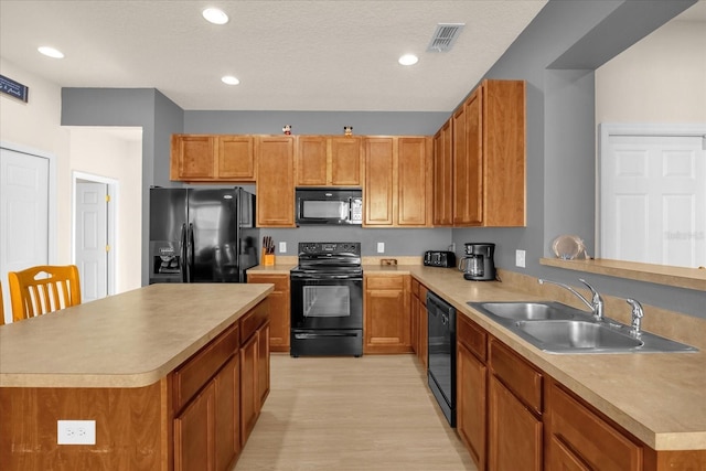 kitchen with kitchen peninsula, sink, light hardwood / wood-style floors, and black appliances