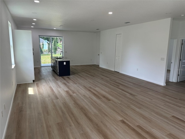 spare room with recessed lighting, a sink, baseboards, and wood finished floors