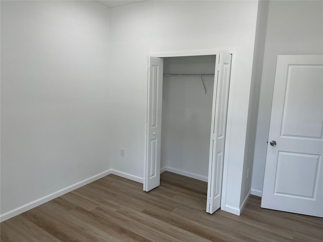 unfurnished bedroom with a closet, baseboards, and wood finished floors