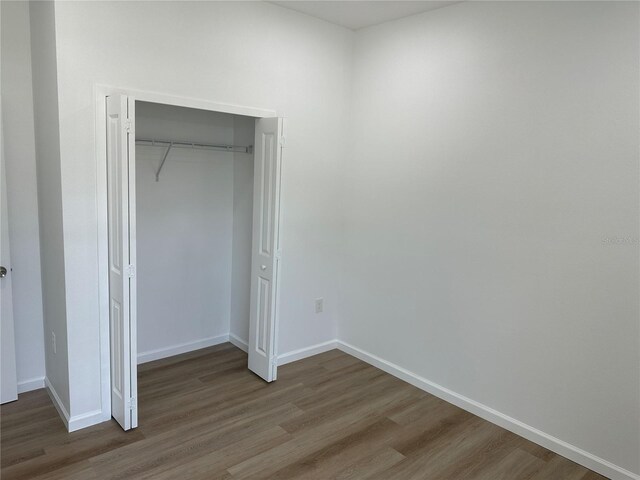 unfurnished bedroom featuring a closet, baseboards, and wood finished floors