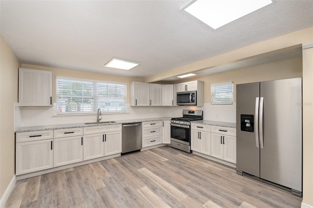 kitchen with plenty of natural light, light wood-type flooring, sink, and appliances with stainless steel finishes