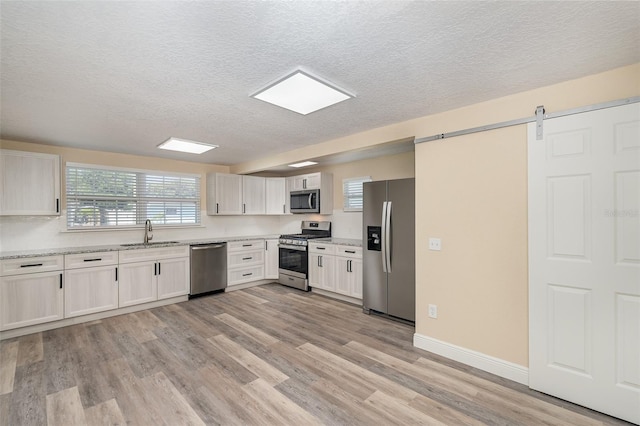 kitchen with white cabinetry, sink, appliances with stainless steel finishes, and light hardwood / wood-style flooring