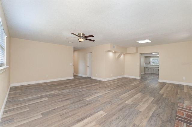 unfurnished living room with ceiling fan, a textured ceiling, and light hardwood / wood-style flooring