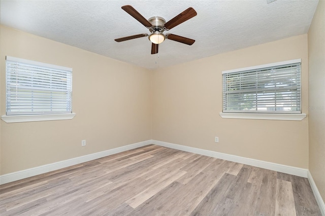 empty room with a textured ceiling, light wood-type flooring, and ceiling fan