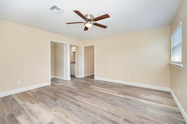 empty room featuring a textured ceiling, light hardwood / wood-style floors, and ceiling fan