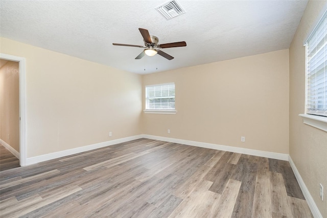 spare room featuring ceiling fan, light hardwood / wood-style flooring, and a textured ceiling