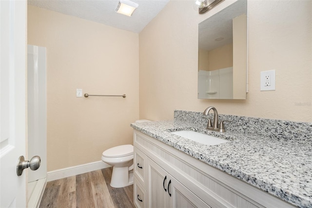 bathroom with toilet, vanity, a textured ceiling, and hardwood / wood-style flooring