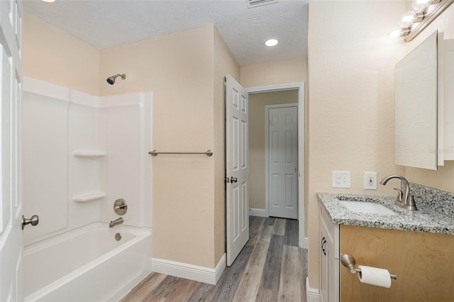 bathroom featuring hardwood / wood-style floors, vanity, shower / bath combination, and a textured ceiling