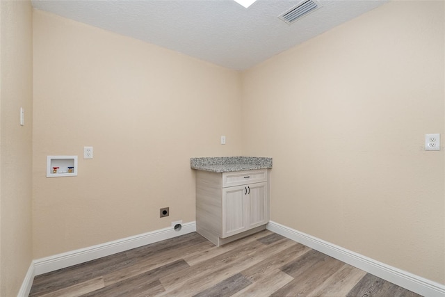 laundry area featuring electric dryer hookup, cabinets, washer hookup, a textured ceiling, and light hardwood / wood-style floors