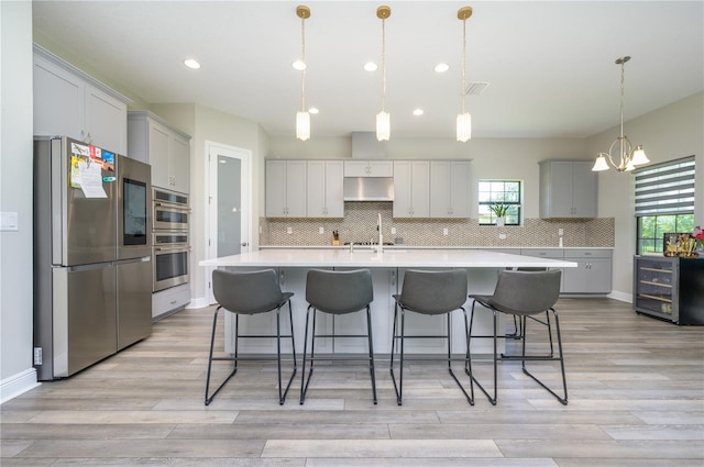 kitchen with pendant lighting, a large island, light wood-type flooring, and appliances with stainless steel finishes