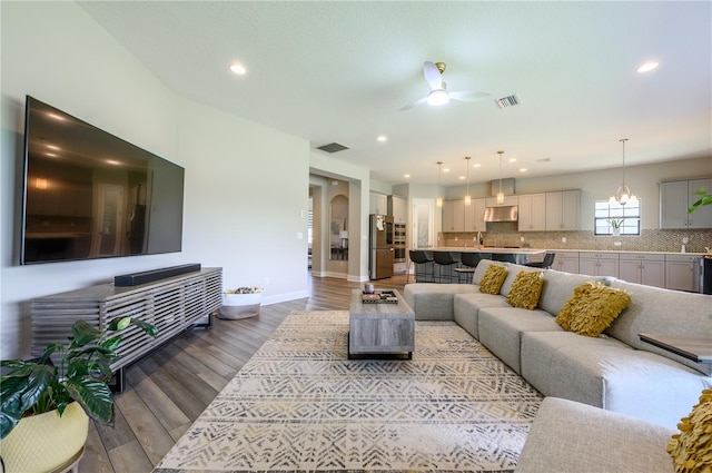 living room with hardwood / wood-style floors and ceiling fan with notable chandelier