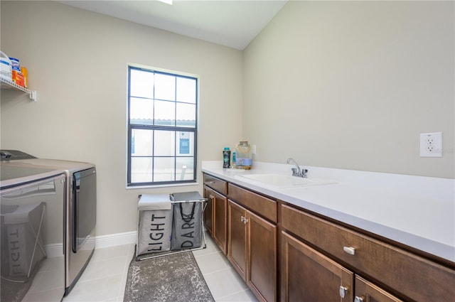 laundry room with washing machine and dryer, sink, light tile patterned flooring, and cabinets