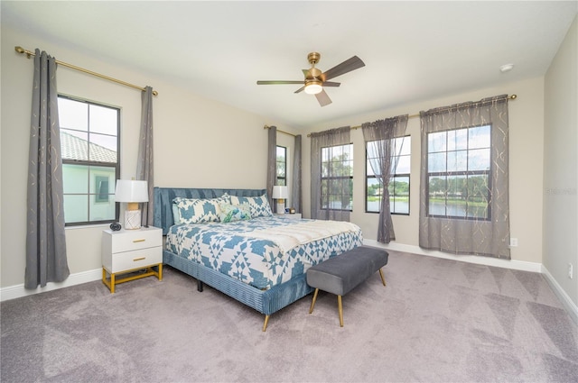 carpeted bedroom featuring ceiling fan and multiple windows