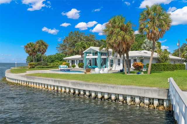 back of property with a water view, a patio, and a lawn