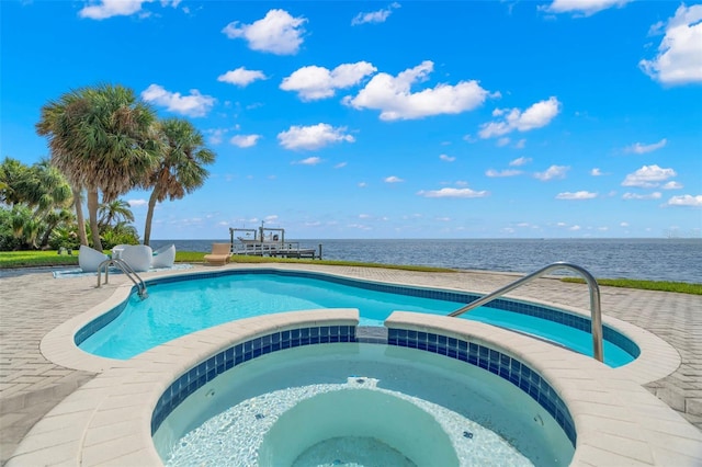 view of pool featuring a pool with connected hot tub, a water view, and a patio