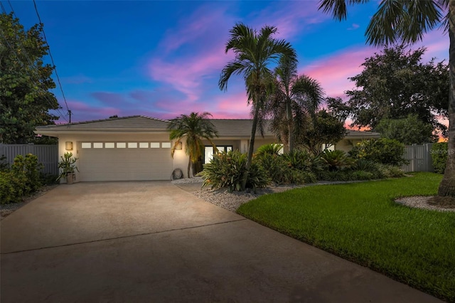 view of front of house with stucco siding, concrete driveway, a front yard, fence, and a garage