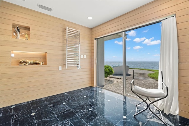 unfurnished room featuring radiator heating unit, wooden walls, and a water view