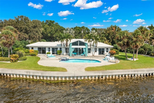 rear view of house featuring a water view, a patio area, and a lawn