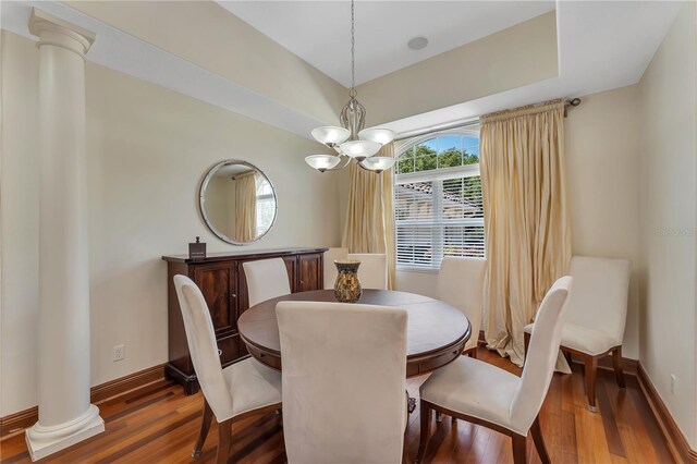 dining room with an inviting chandelier, decorative columns, and dark hardwood / wood-style floors