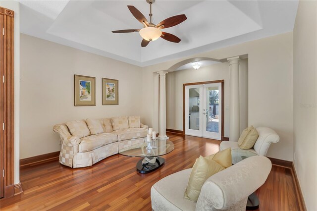 living room with a tray ceiling, ceiling fan, hardwood / wood-style flooring, and french doors