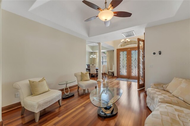 living room featuring decorative columns, french doors, ceiling fan with notable chandelier, and hardwood / wood-style floors