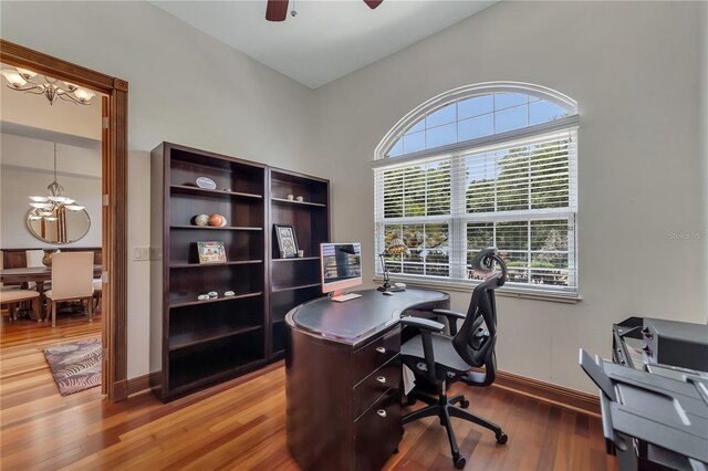 home office with ceiling fan with notable chandelier and wood-type flooring