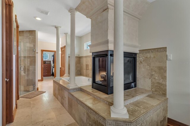 bathroom with tile patterned flooring, ornate columns, shower with separate bathtub, and a multi sided fireplace