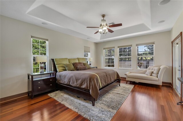 bedroom featuring ceiling fan, a raised ceiling, and dark hardwood / wood-style flooring