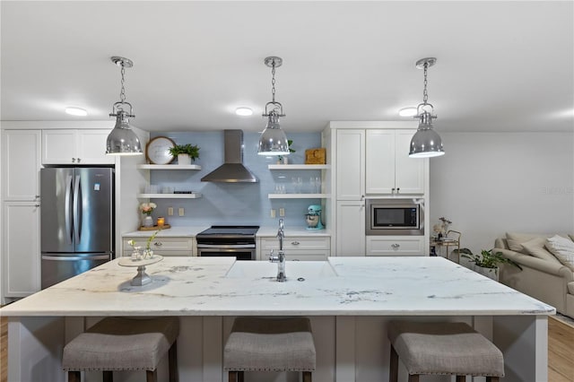 kitchen featuring wall chimney range hood, white cabinetry, stainless steel appliances, and light hardwood / wood-style floors