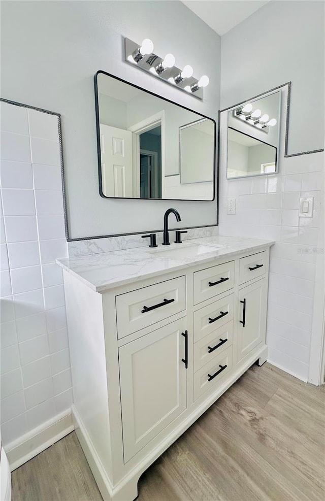 bathroom with tile walls, wood finished floors, and vanity