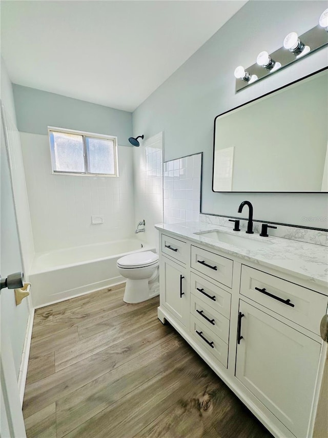 bathroom with toilet, shower / tub combination, wood finished floors, and vanity