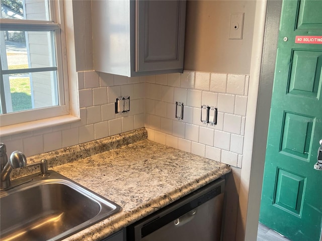 kitchen with dishwasher, light countertops, a sink, and decorative backsplash