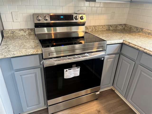 kitchen with dark wood-style flooring, stainless steel range with electric cooktop, and decorative backsplash