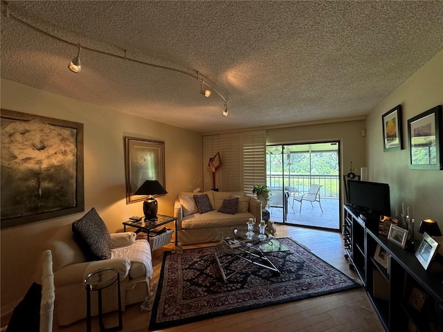 living room with a textured ceiling, rail lighting, and hardwood / wood-style flooring