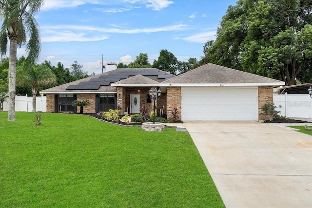 view of front facade featuring driveway, solar panels, an attached garage, fence, and a front yard