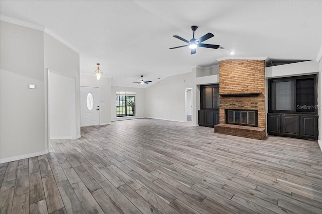 unfurnished living room with vaulted ceiling, a fireplace, crown molding, hardwood / wood-style flooring, and ceiling fan