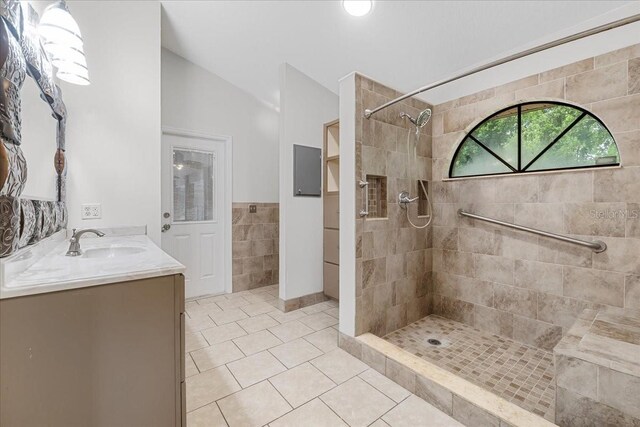 bathroom featuring vanity, lofted ceiling, tiled shower, and tile patterned flooring