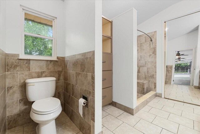 bathroom with tile walls, tile patterned flooring, toilet, and plenty of natural light