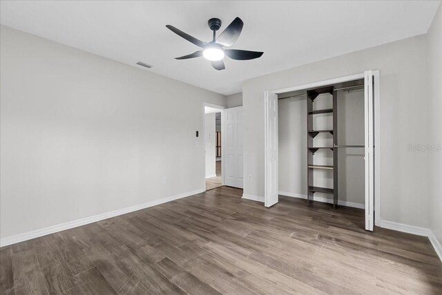 unfurnished bedroom featuring ceiling fan, a closet, and hardwood / wood-style flooring