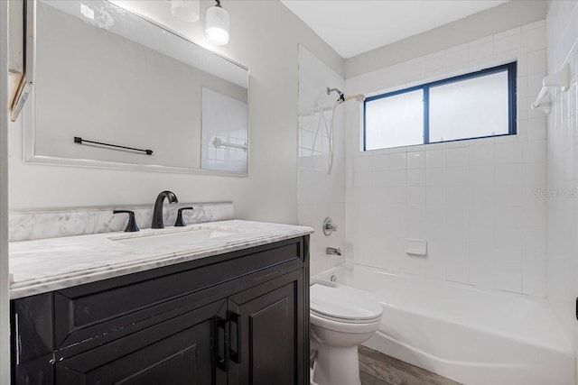 full bathroom with hardwood / wood-style floors, tiled shower / bath, toilet, and vanity