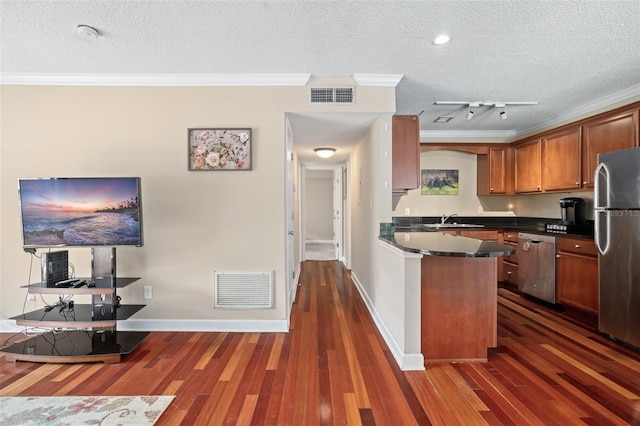 kitchen featuring appliances with stainless steel finishes, crown molding, a textured ceiling, track lighting, and dark wood-type flooring