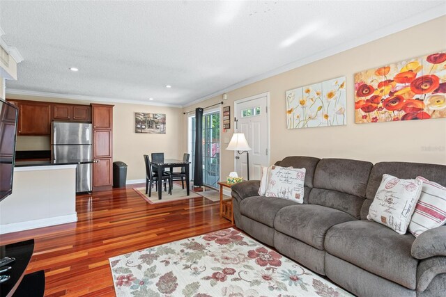 living room featuring dark wood-type flooring, ornamental molding, and a textured ceiling