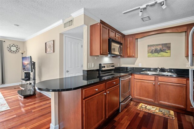 kitchen with dark hardwood / wood-style floors, track lighting, appliances with stainless steel finishes, sink, and a textured ceiling