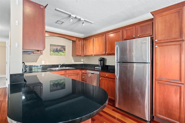 kitchen featuring dark hardwood / wood-style floors, appliances with stainless steel finishes, sink, rail lighting, and a textured ceiling