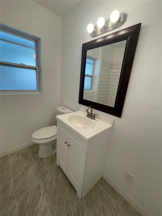 bathroom with plenty of natural light, toilet, tile patterned floors, and vanity