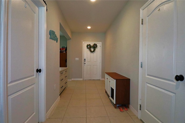 hall featuring light tile patterned floors and baseboards